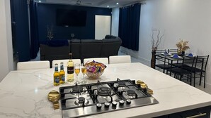A modern kitchen with a gas stove, marble countertops, and a dining area with a table set for two. - St. Rose Villa (Savannes)