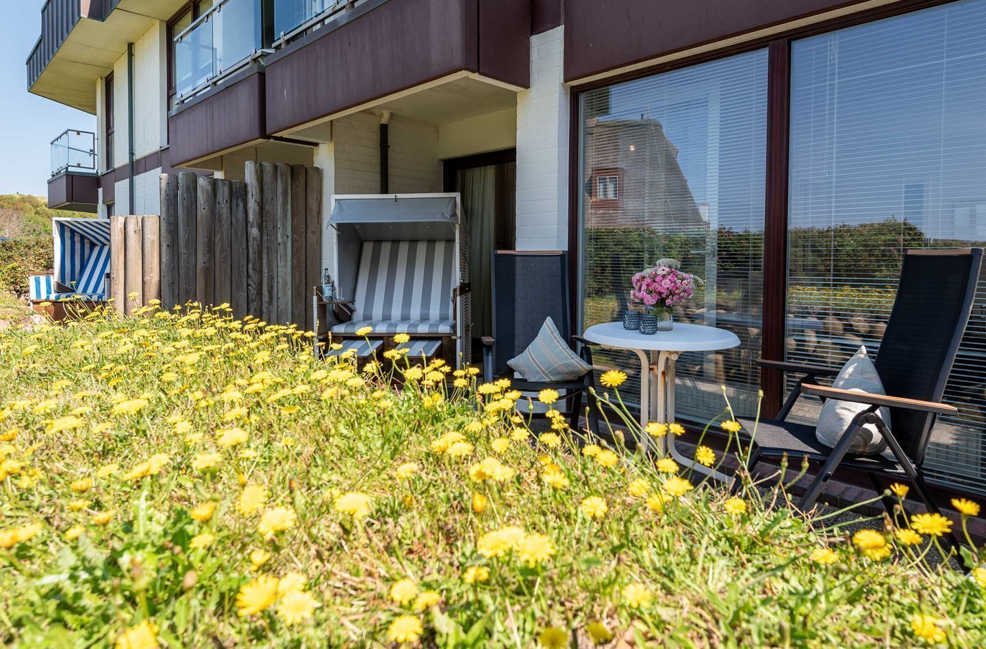 Un edificio moderno con balcón, mobiliario exterior y jardín de flores.