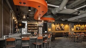 A bar area with a curved ceiling, bar stools, and a variety of bottles and glasses on shelves.