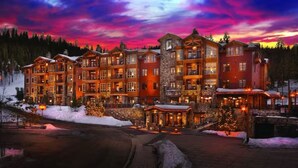 A multi-story lodge with a stone facade, multiple balconies, and a snow-covered ground.