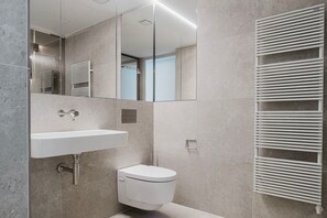 Ein modernes Badezimmer mit integriertem Waschbecken, Toilette und Handtuchhalter.
