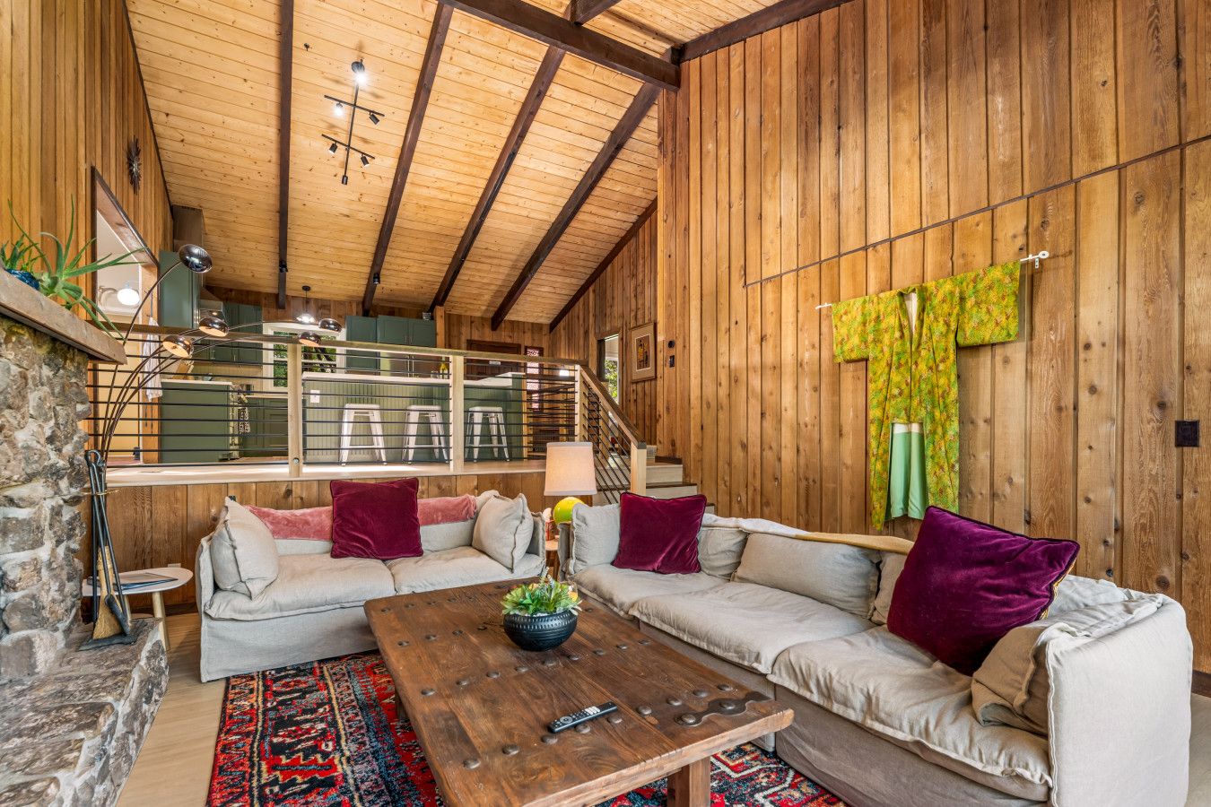 A cozy interior with a wooden ceiling, a sofa set, a coffee table, and a staircase.