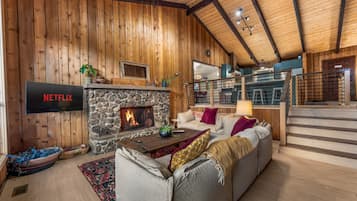 A cozy living room with a stone fireplace, a sofa, and a Netflix sign.