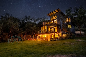 A two-story house with a balcony, surrounded by trees and a grassy yard. - Hot Tub|Riverfront|15 min to Hot Springs & Skiing (Glenwood Springs)