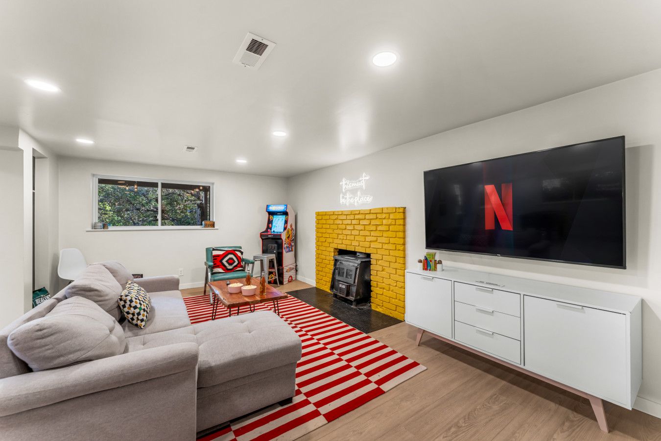 A modern living room with a flat-screen TV, a fireplace, and a gaming console.