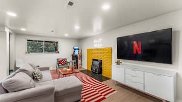 A modern living room with a flat-screen TV, a fireplace, and a gaming console.