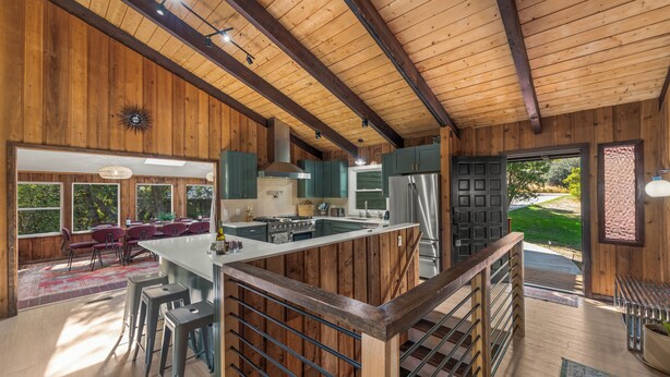 A spacious kitchen with wooden beams, a large island, and green cabinets.