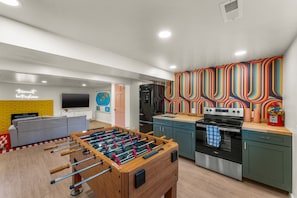 A modern living room with a foosball table, a flat-screen TV, and a sofa. - Hot Tub|Riverfront|15 min to Hot Springs & Skiing (Glenwood Springs)