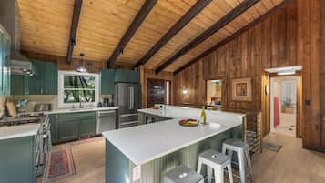 A spacious kitchen with a large island, stainless steel appliances, and wooden paneling.