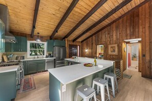 A spacious kitchen with a large island, stainless steel appliances, and wooden paneling.