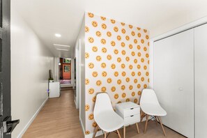 A hallway with a white wardrobe, two white chairs, and a wall with a smiley face pattern.