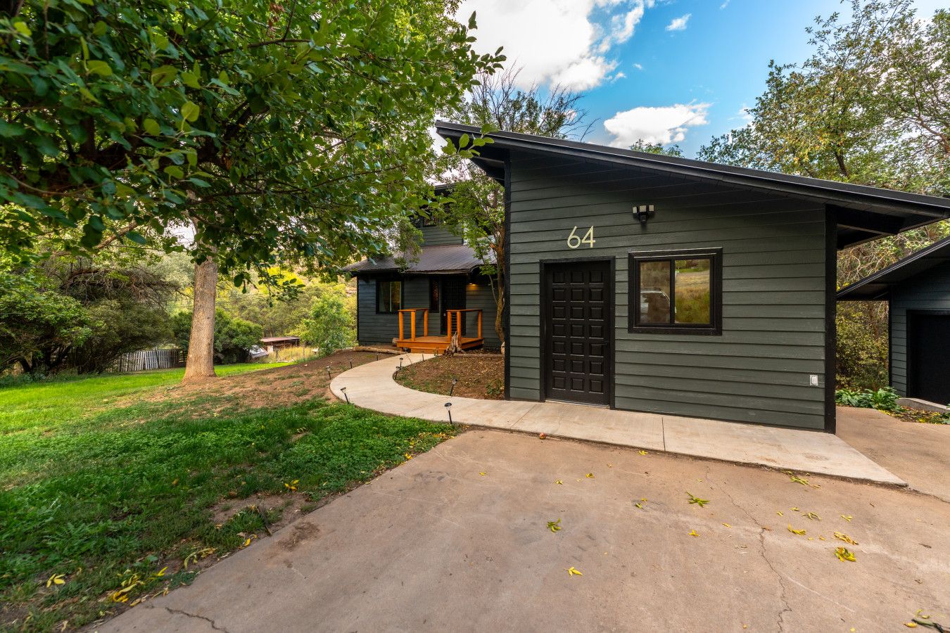 A modern two-story house with a dark exterior, a visible garage, and a well-maintained lawn.