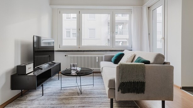 A modern living room with a sofa, a coffee table, a TV, and a radiator.