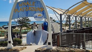 L’entrée du parc aquatique « Whale Playground » est signalée par un panneau bleu et jaune, soutenu par une structure arquée en métal.