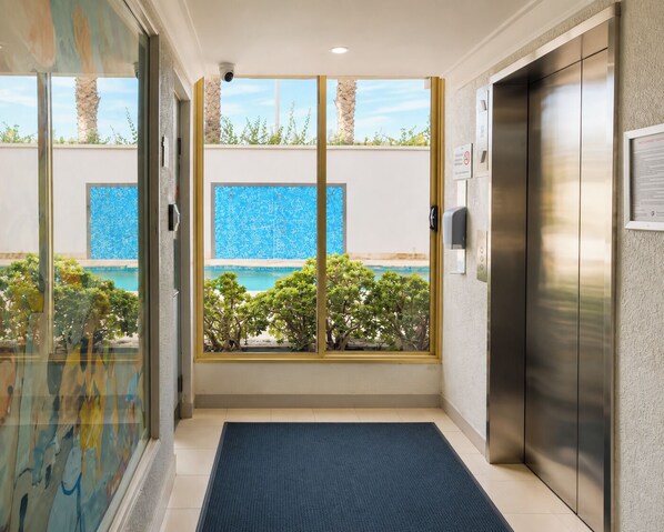An elevator with a view of a swimming pool and greenery outside.