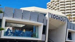 Un bâtiment moderne sur lequel on peut lire l’inscription « POINT DE VUE », doté d’un balcon en verre où sont assis des gens.