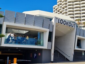 A modern building with a 'LOOKOUT' sign, featuring a glass balcony with people seated.