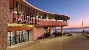 A modern building with a curved facade and a sign reading 'Scarborough Beach Pool'. - Sunset Shores Scarborough (Scarborough)