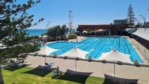 A swimming pool with multiple lanes, sun loungers, and a building in the background. - Sunset Shores Scarborough (Scarborough)