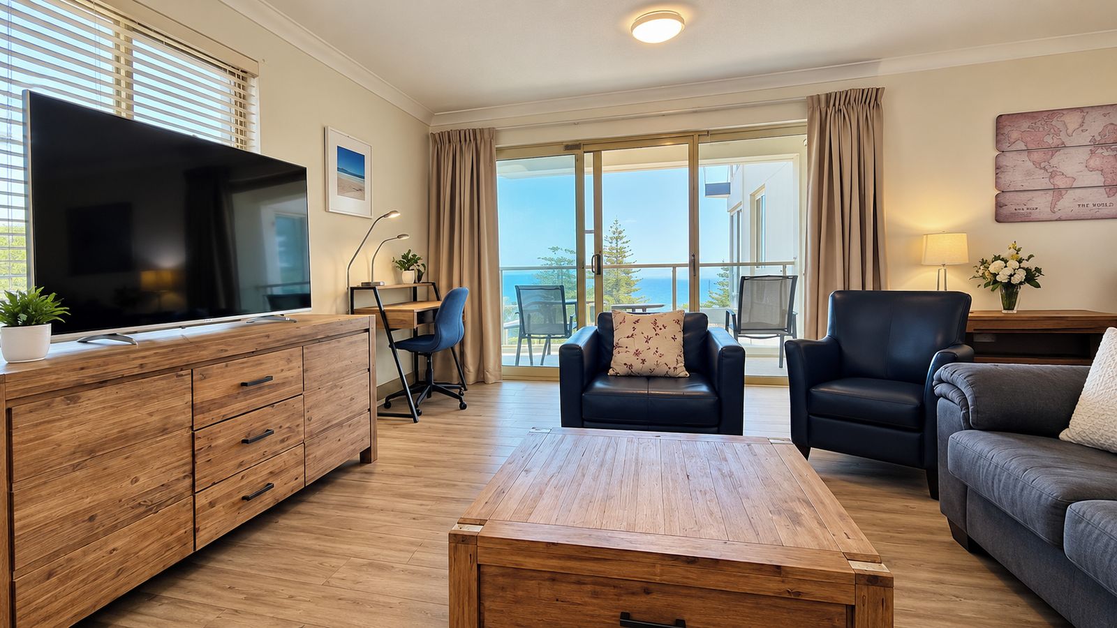 A modern living room with a wooden coffee table, leather sofas, a TV, and a balcony with a view.