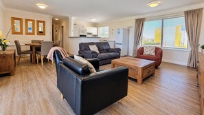 A modern living room with a sofa, a coffee table, and a dining area with chairs and a table. - Sandcastles at the Beach – Outstanding Location! (Scarborough)