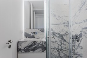 Bathroom features a large mirror, glass shower enclosure, and a marble sink.