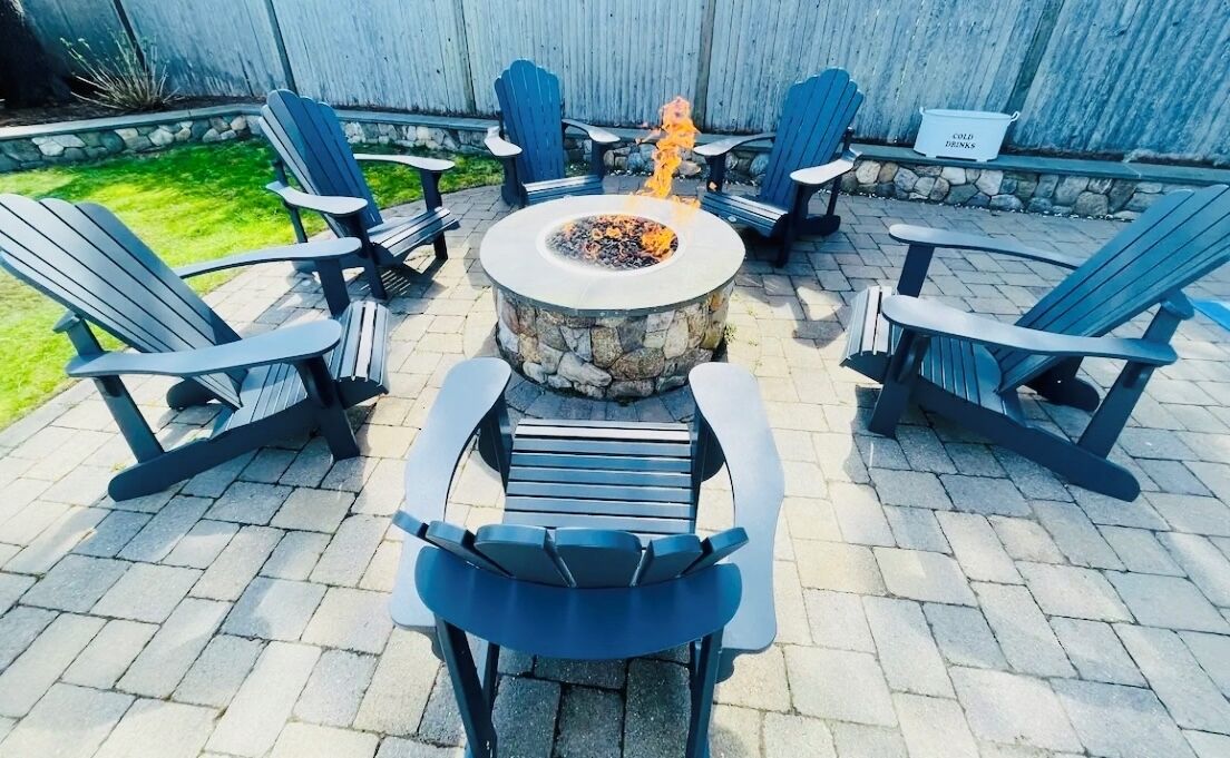Eine Terrasse mit Adirondack-Stühlen, einer Steinkaminfeuerstelle und einem Schild, das kalte Getränke anzeigt.