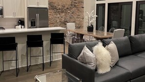 Eine moderne Küche mit weißen Schränken, einer Ziegelwand als Blickfang und einem Edelstahl-Kühlschrank.