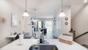 Een moderne keuken met een centraal eiland, een roestvrijstalen spoelbak en hangende lampen.