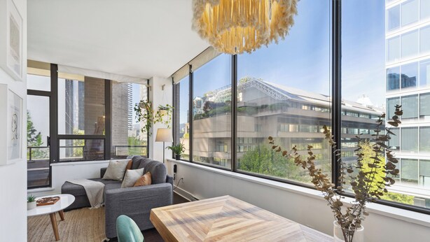 Una sala moderna con un ventanal grande, una mesa de comedor de madera y un sofá.