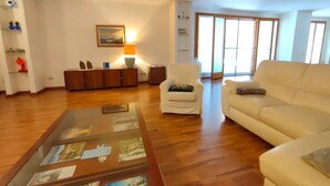 Una sala de estar con sofá, sillón, mesa de centro y suelo de madera.