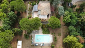 Vista aérea de una propiedad residencial con piscina, paneles solares y jardín.