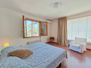 Un dormitorio con una cama, una silla, un ventanal y un radiador.