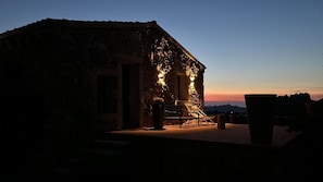 A stone building with a patio, a chair, and a potted plant.