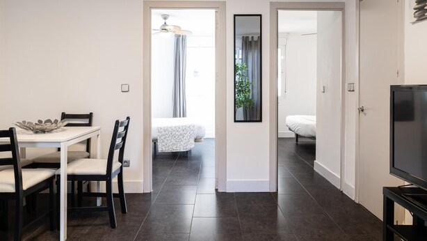 A modern, well-lit room with a dining area, a bed, and a TV. - Holidays2Malaga Los Negros RoofTop for common use (Málaga)