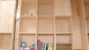 Une bibliothèque en bois, dotée de plusieurs compartiments, dont certains sont remplis de livres et d’autres sont vides.