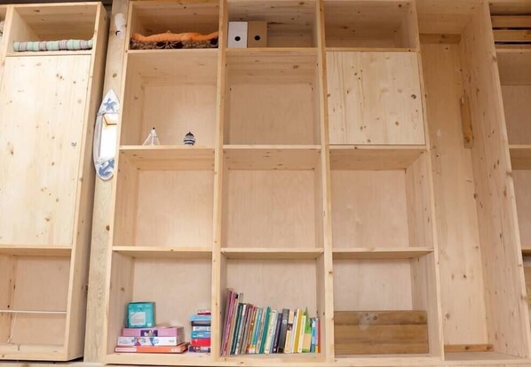 A wooden bookshelf with multiple compartments, some filled with books and others empty.