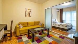 A room with a sofa, a bed, a small table, and a colorful rug. - Primorski 2bdrm Central Apartment (Varna)
