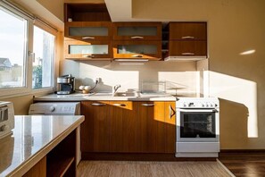 A modern kitchen with wooden cabinets, a built-in oven, a sink, and a window providing natural light.