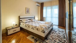 A bedroom with a bed, bedside table, and a window with curtains. - Primorski 2bdrm Central Apartment (Varna)