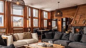 A cozy interior with a fireplace, wooden furniture, and large windows. - Chalet d’Albiez: 360° Mountain Views and Panoramic Terrace (Albiez-Montrond)