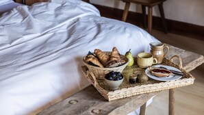 A bed with white linens, a wooden table with a basket of bread, a bowl of blueberries, a pear, a mug, a jug, and a plate with a pastry. - Chalet d’Albiez: 360° Mountain Views and Panoramic Terrace (Albiez-Montrond)