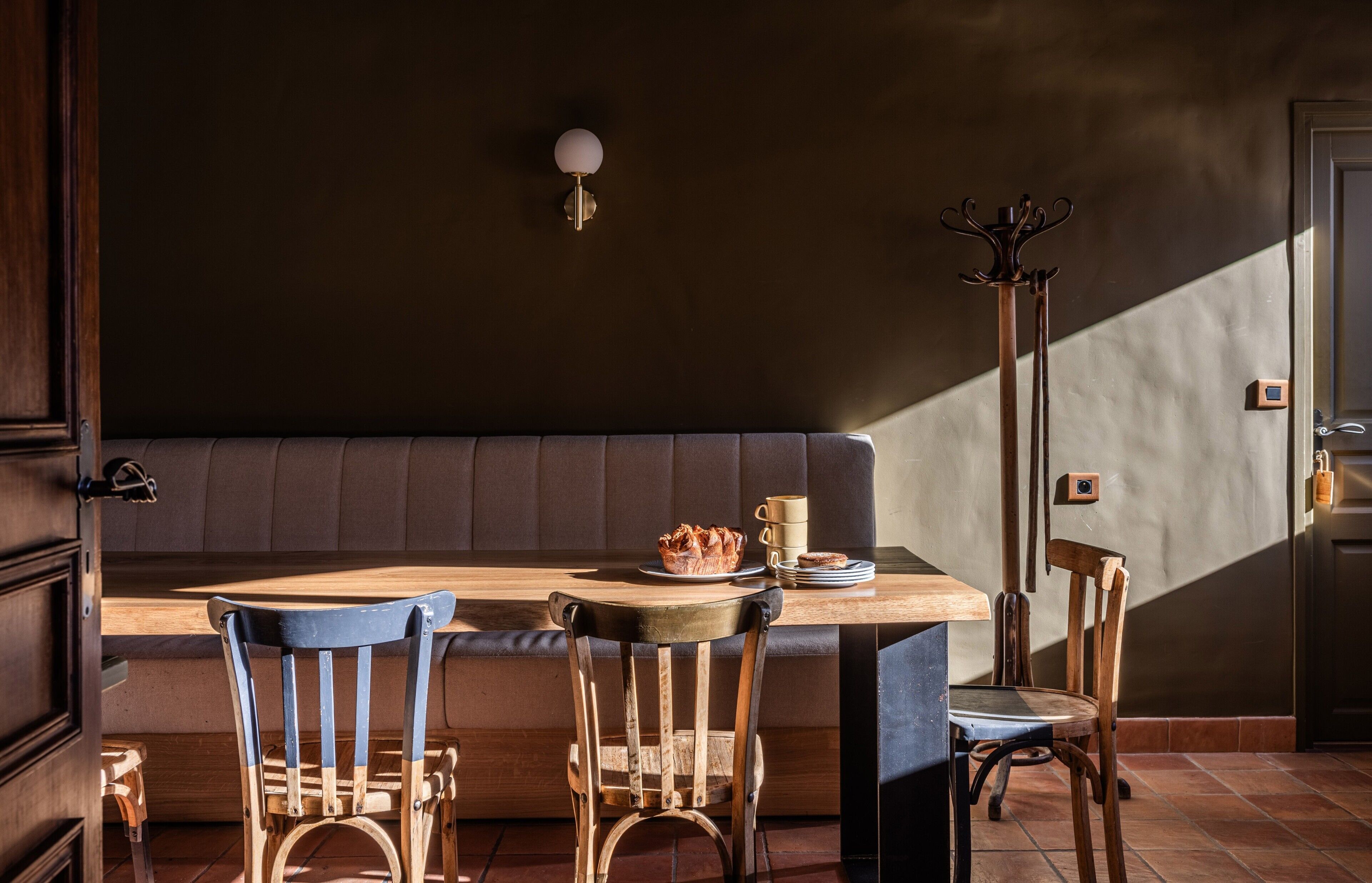 A wooden table with chairs, a bench, and a wall-mounted light fixture.