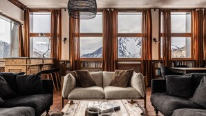 A cozy living room with a sofa, two armchairs, a wooden coffee table, and a bookshelf. - Chalet d’Albiez: 360° Mountain Views and Panoramic Terrace (Albiez-Montrond)
