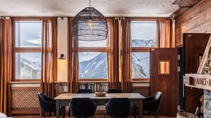 A dining area with a wooden table, black chairs, and a hanging light fixture. - Chalet d’Albiez: 360° Mountain Views and Panoramic Terrace (Albiez-Montrond)
