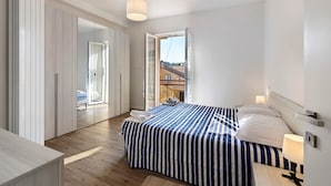 A modern hotel room with a large bed, a bedside table, a hanging light fixture, and a view of the outside. - Apartment 'Il Borgo Incantato with Garage' with Wi-Fi and Air Conditioning (Finale Ligure)