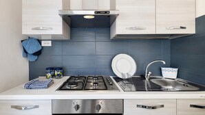 A modern kitchen with a gas stove, stainless steel appliances, and a blue tiled backsplash. - Apartment 'Il Borgo Incantato with Garage' with Wi-Fi and Air Conditioning (Finale Ligure)