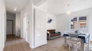 A modern interior with a dining area, a sofa, and a hallway leading to another room. - Apartment 'Il Borgo Incantato with Garage' with Wi-Fi and Air Conditioning (Finale Ligure)