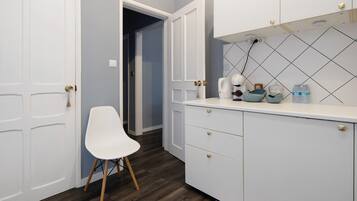 Una cocina moderna con armarios blancos, una silla blanca y salpicadero de azulejos.