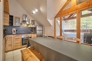 A kitchen with wooden cabinets, a stainless steel range hood, and a dining area with a table and chairs.
